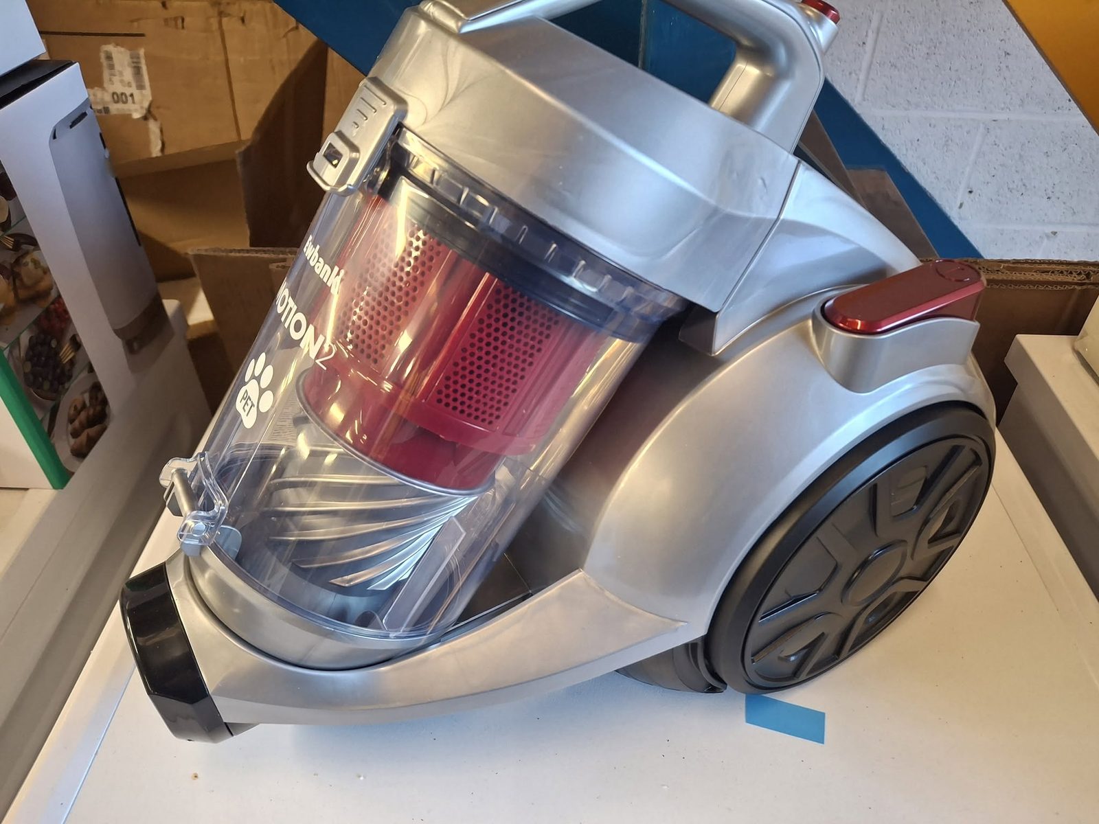 A silver and red cylinder vacuum cleaner on the shop counter