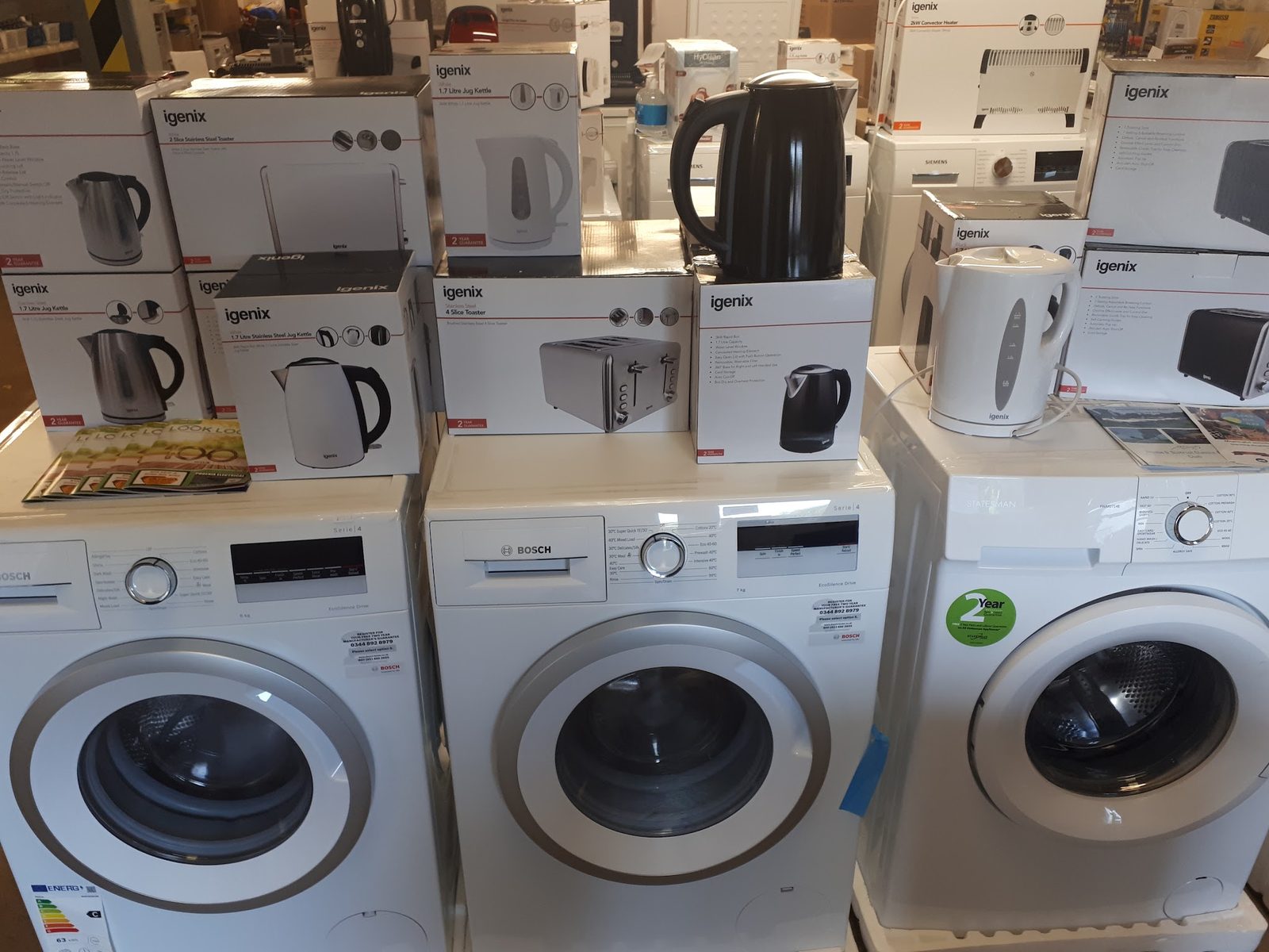 Boxed kettles and toasters on top of a row of washing machines